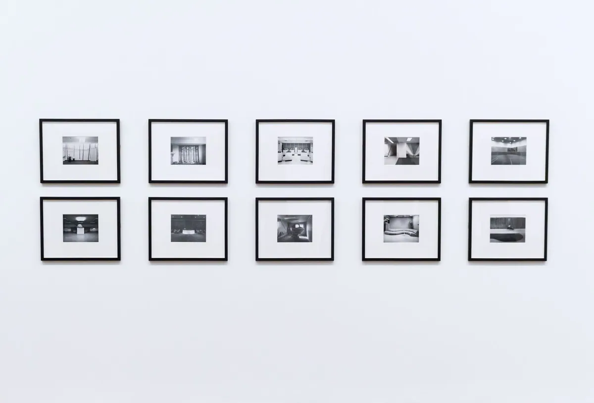 Evenly spaced grid of ten slim black framed pictures hung as a gallery wall