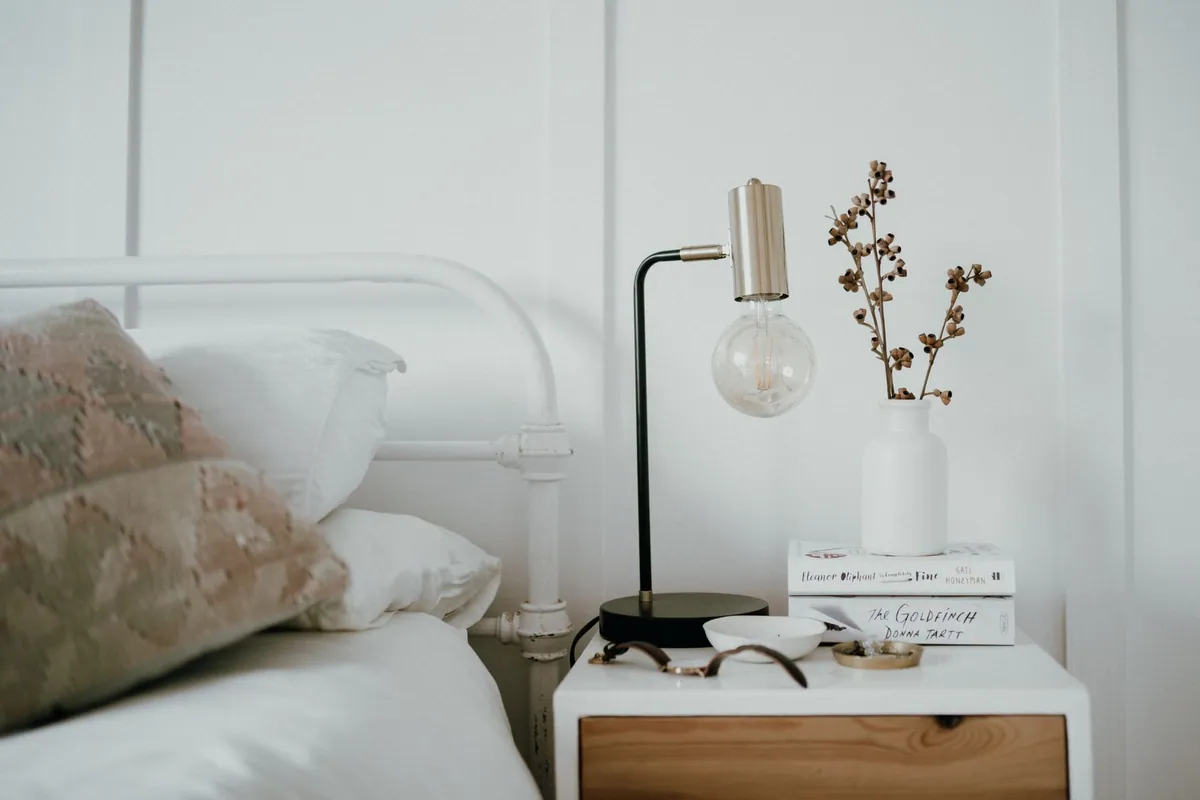 Small slim table lamp on a narrow bedside table in a compact bedroom